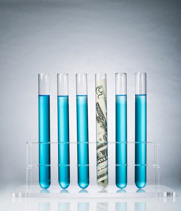 Six test tubes, five with blue liquid and one containing money