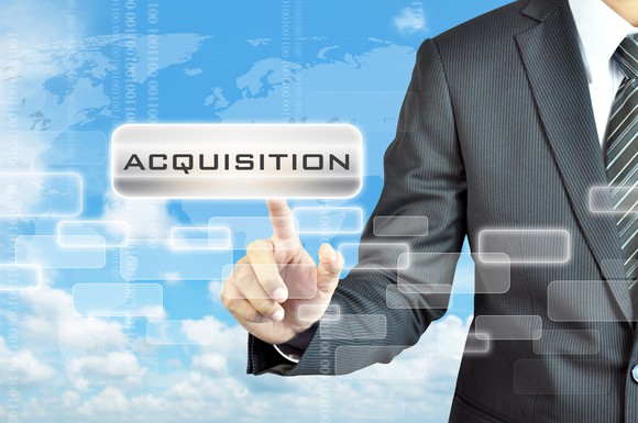 Man in suit pointing to the word "acquisition" shown in foreground