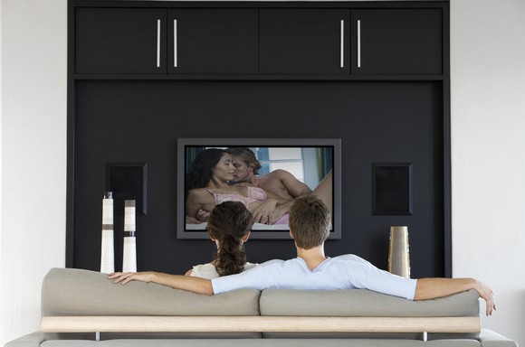 Back view of couple watching romantic movie on television.