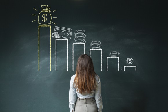 A woman looks at a chalkboard showing a chart representing money.