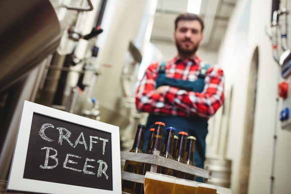 Craft brewer standing behind and 8-pack of craft beer