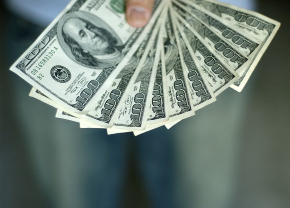 Hand holding 10 hundred-dollar bills.