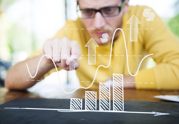 A man points toward drawings of an ascending bar chart.