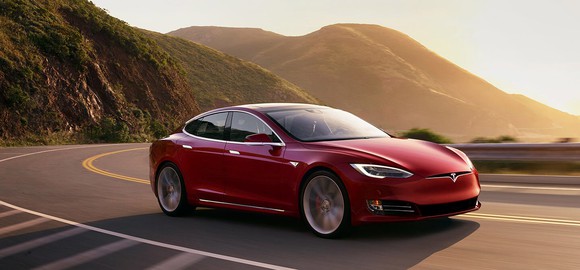 red Tesla car driving on curvy road