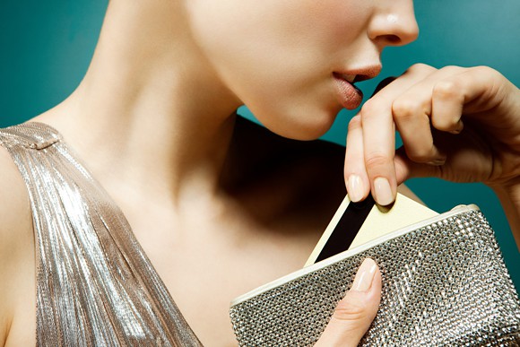 A woman takes a credit card out of a sparkly luxury wallet.