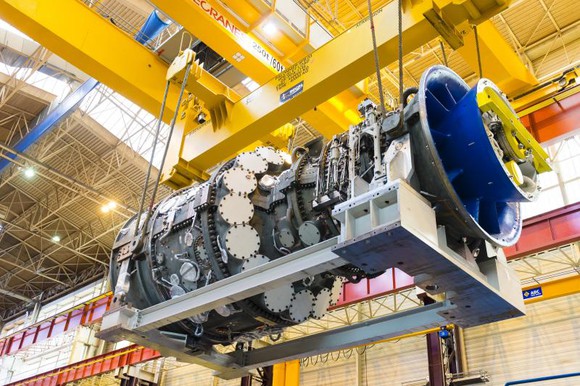 A General Electric gas turbine being hoisted by cables.