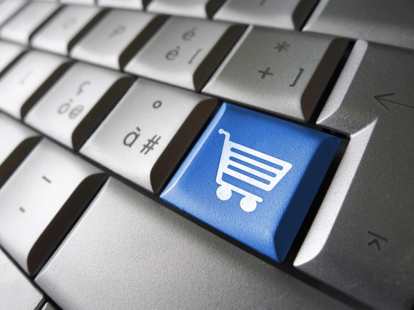 Close-up of a gray computer keyboard with one bright, blue key featuring a white shopping cart icon.
