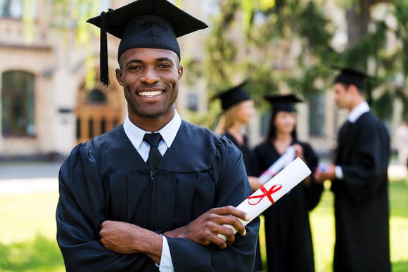 Male in cap and gown holding diploma