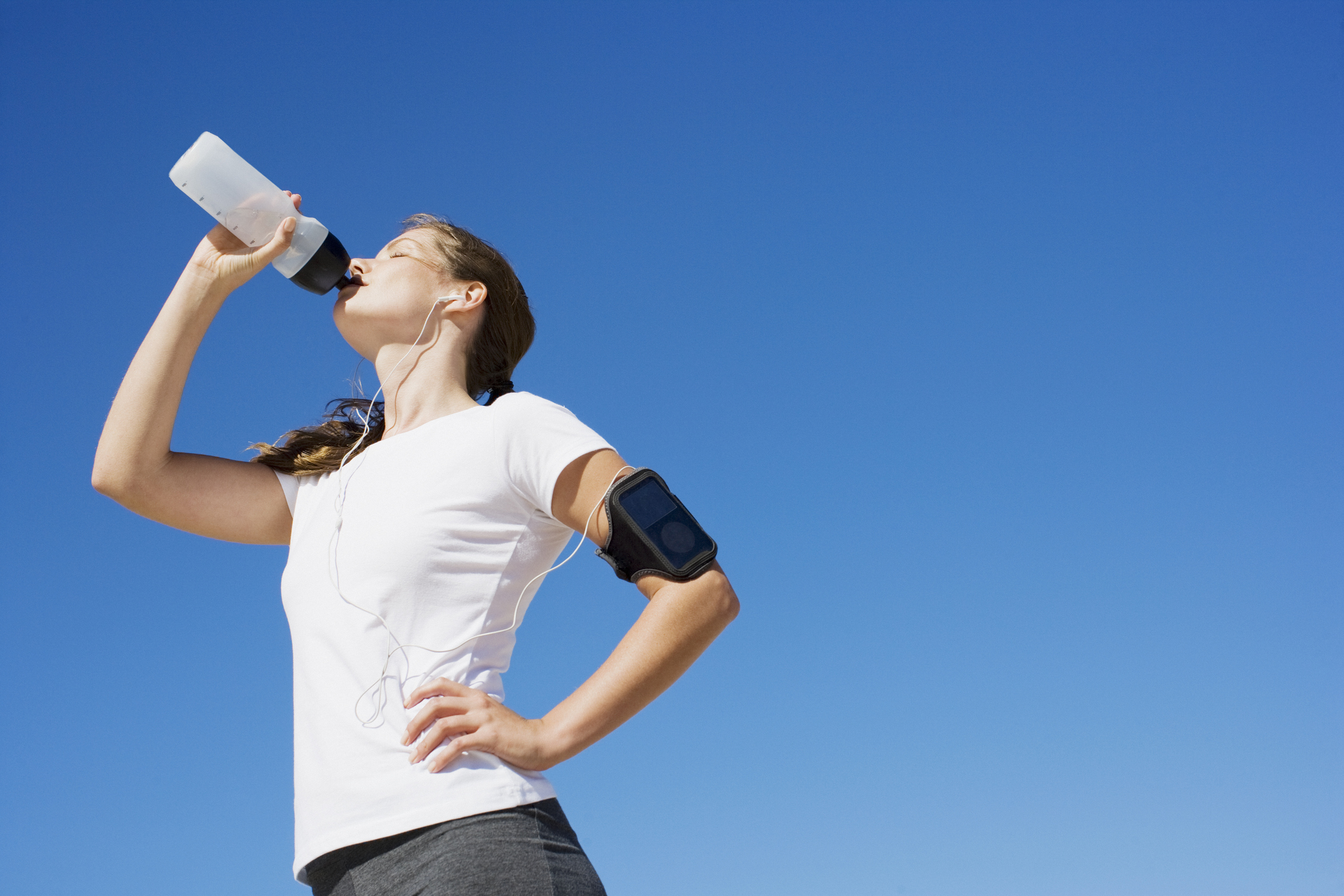 A jogger drinks out of a water bottle.