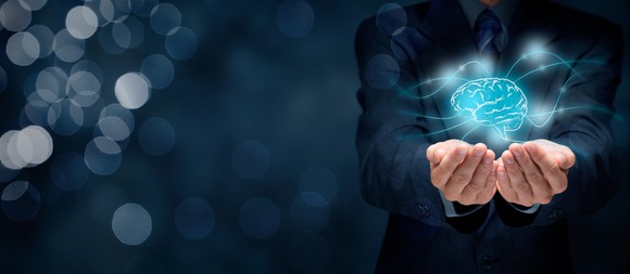 Man dressed in suit with hands extended beneath digital image of a brain