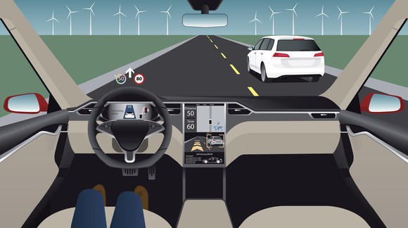 An autonomous vehicle on a road -- person in driver's seat is sitting back with only legs showing on seat.