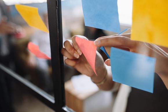 A woman sticking Post-It notes on her wall.
