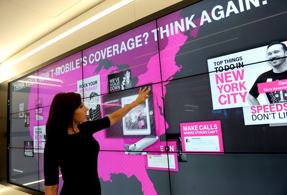 A woman points at a coverage map in a T-Mobile store.
