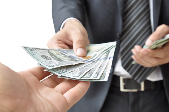 A man hands over multipe hundred dollar bills.