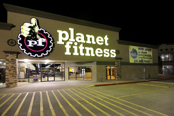 The exterior of a Planet Fitness store at night.