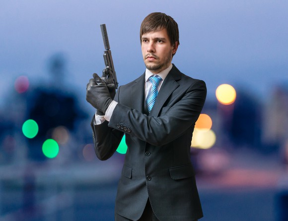 Man in suit holding pistol with silencer