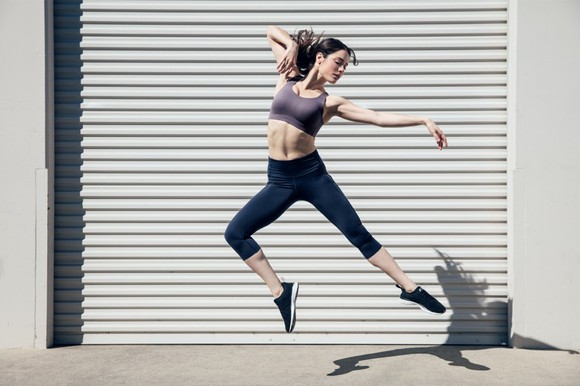 Woman wearing Lululemon's Enlite sports bra leaping into the air like a ballerina.
