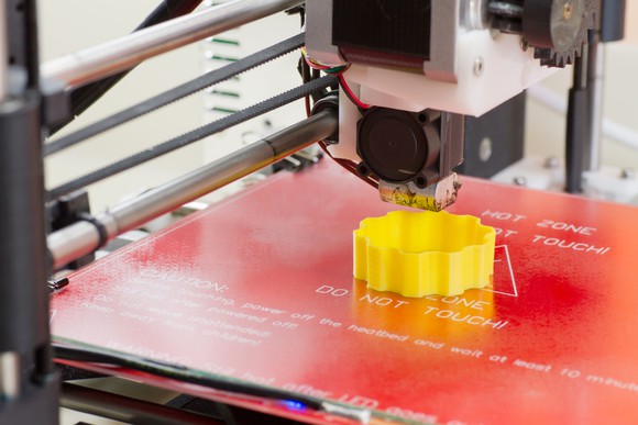 Printing a yellow 3D part with a small 3D printer.