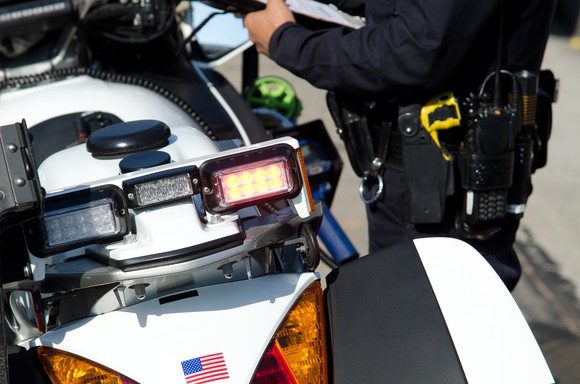 A police officer writing a ticket from his motorcycle.