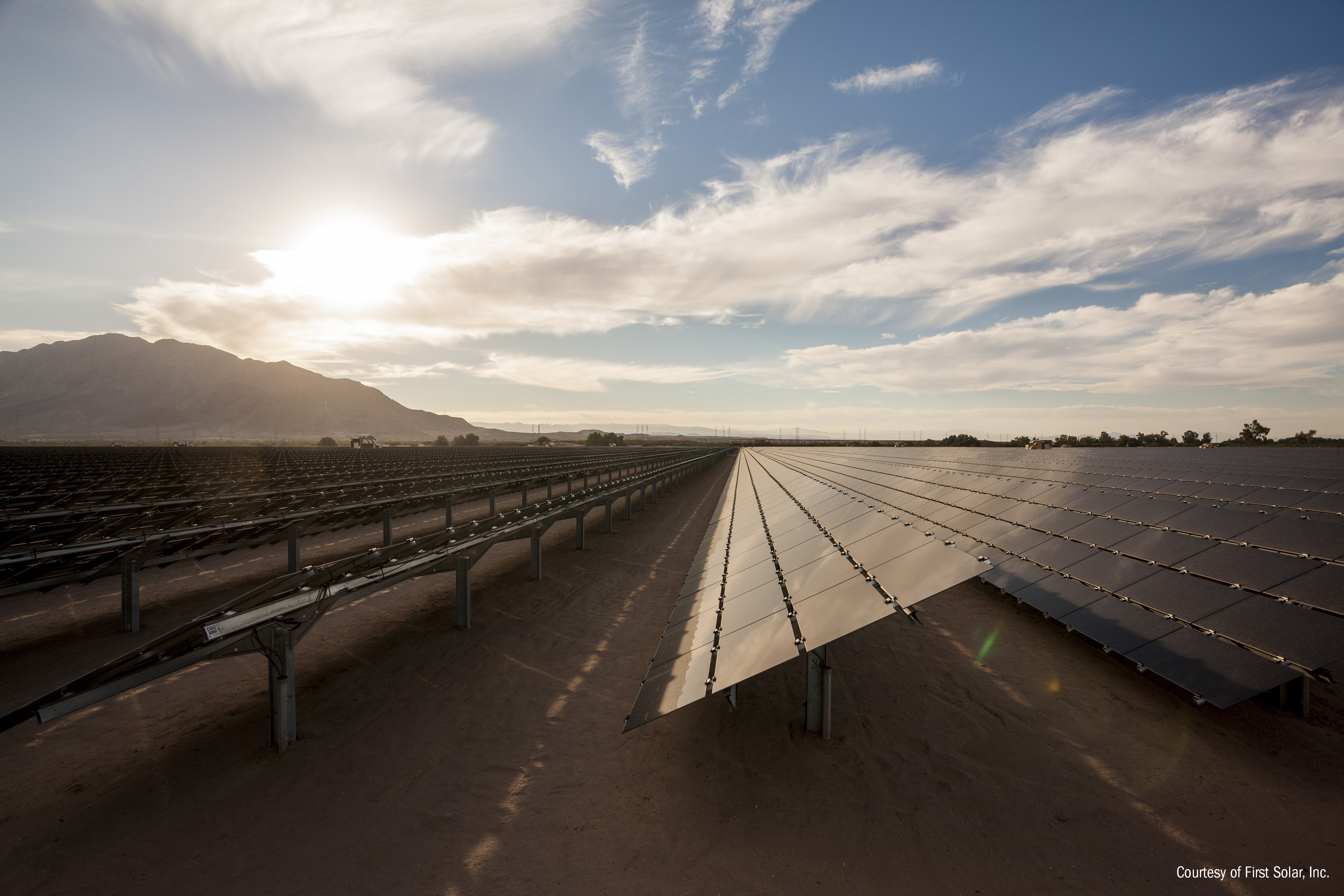 Utility scale solar installation from First Solar with a partially cloudy sky in the background.