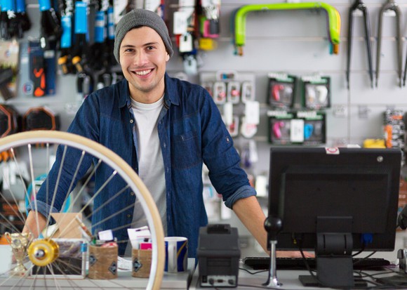 Smiling man standing behind the counter in a bicycle shop.