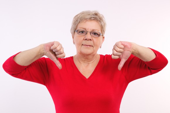 A woman standing with her thumbs pointing down.