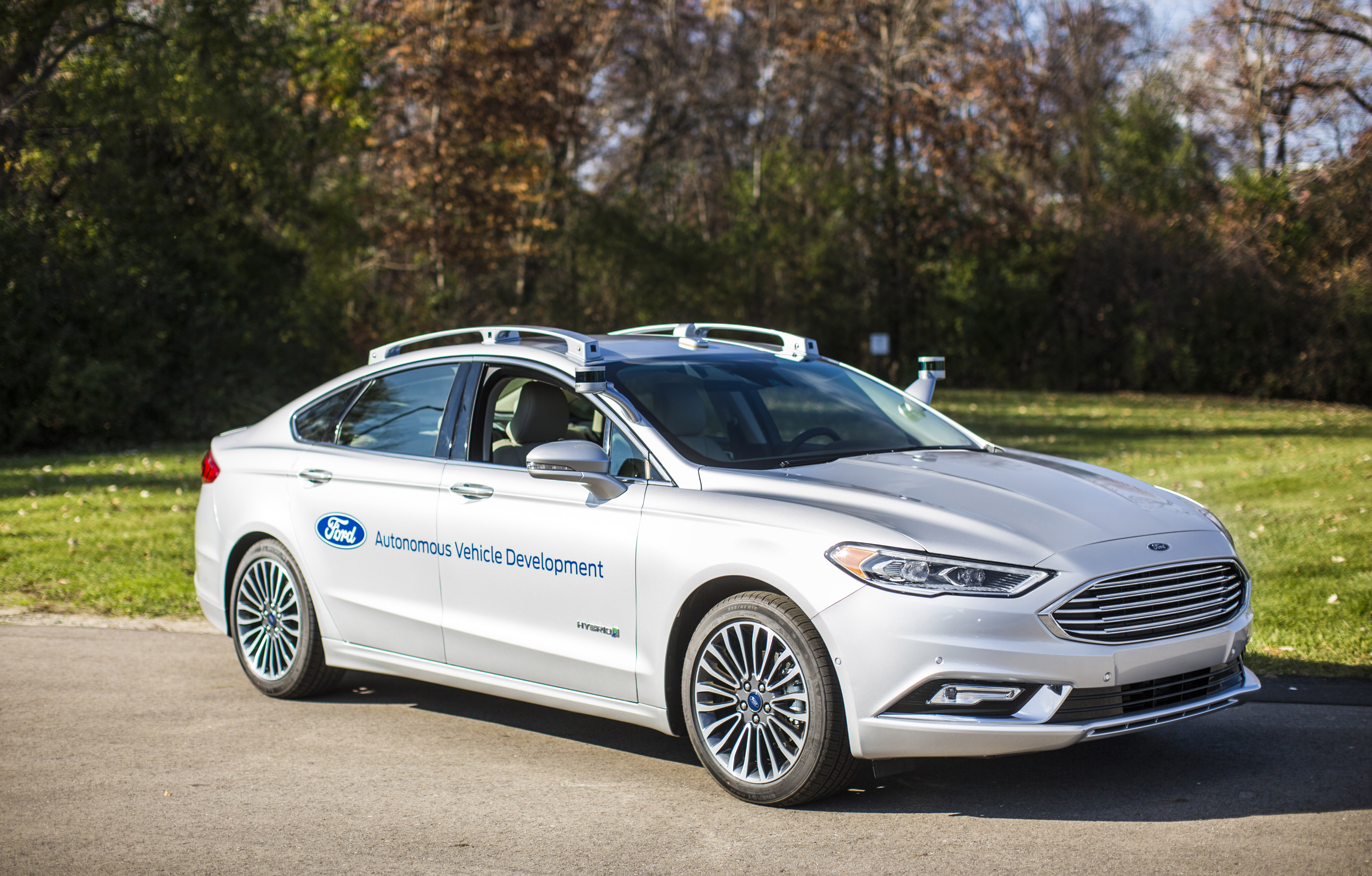 A while Ford Fusion sedan with self-driving sensor hardware visible.
