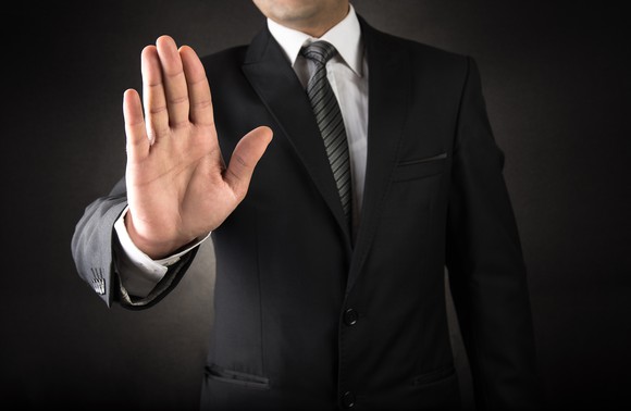 A business man putting up his hand as a form of rejection.