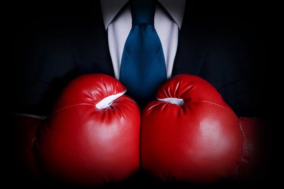 A businessman wearing big red boxing gloves.