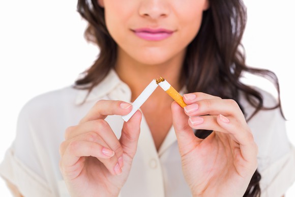 Person breaking a cigarette against a white background.