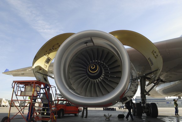 A jet engine being inspected on a tarmac.