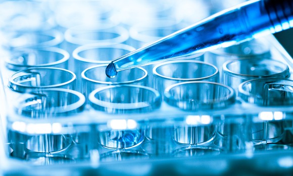 A pipette filling test tubes with a blue liquid.