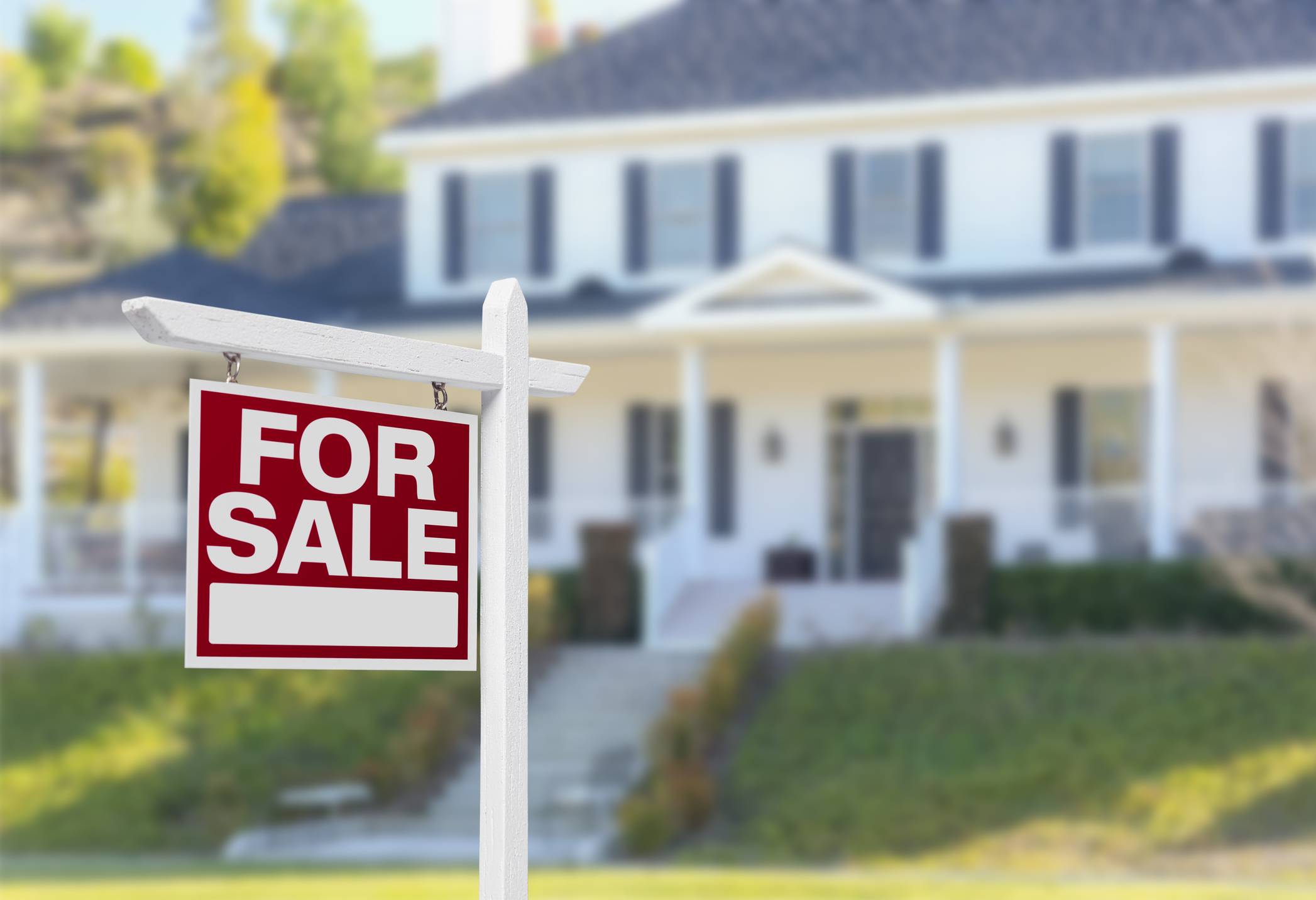 A For Sale sign in front of a house.