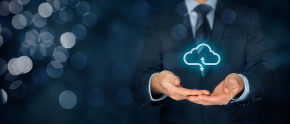 A business person holding a virtual cloud in his hands.