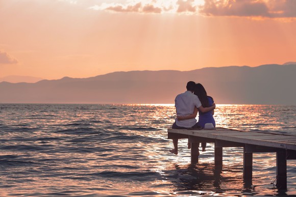 couple sitting on dock watching the sunset