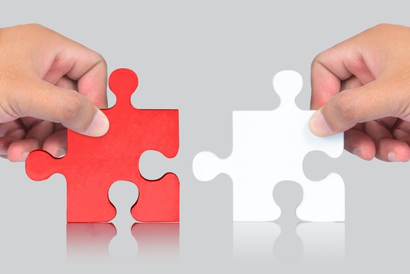 Hands holding red and white jigsaw puzzle pieces
