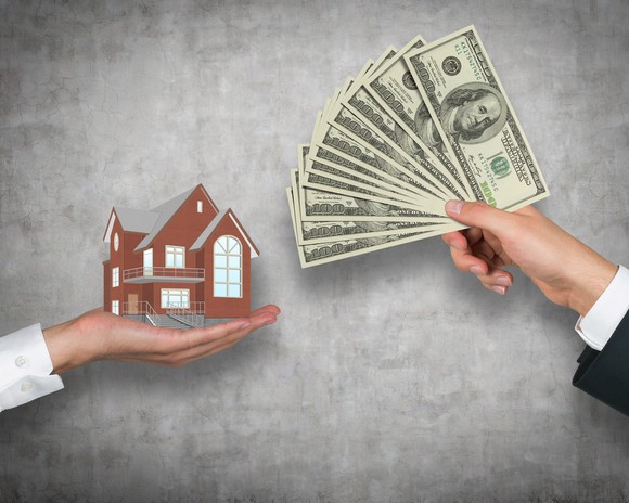 A hand holding up money in return for a miniature house