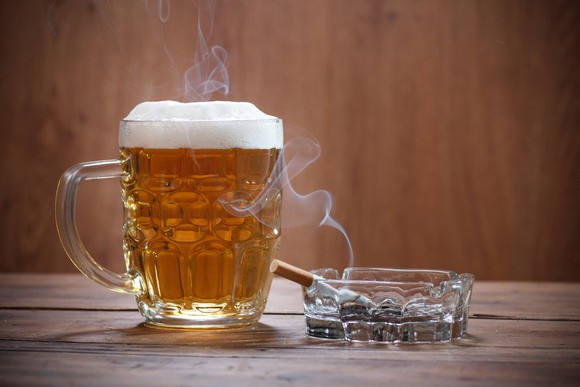 A beer and a half-smoked cigarette sitting on a table