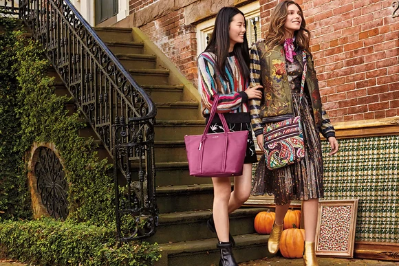Two women at the bottom of stairs carrying Vera Bradley bags.