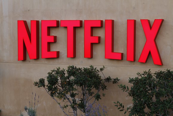 Red Netflix logo on a grey stone wall outside the company's headquarters in Los Gatos, Calif.
