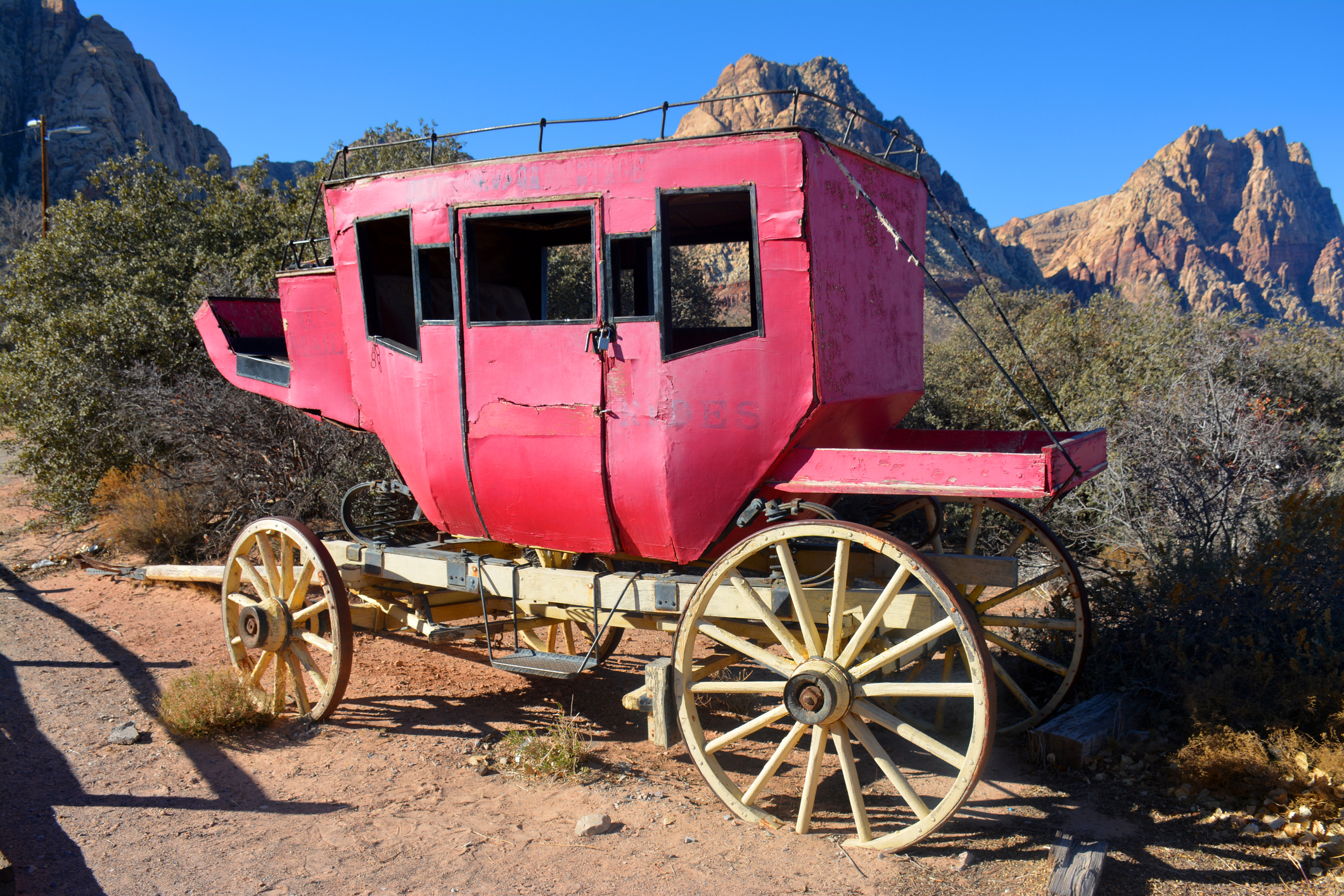 A broken-down stagecoach parked in the desert.