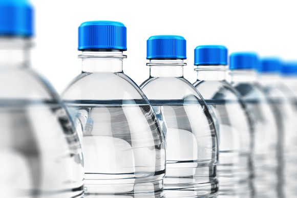 A line of water bottles with blue tops.