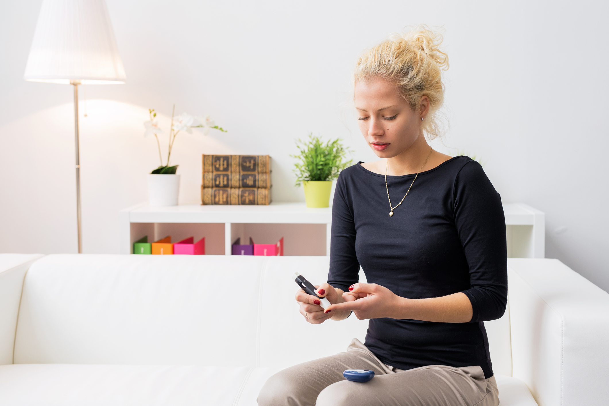 A woman sitting on a couch with a diabetes lancet