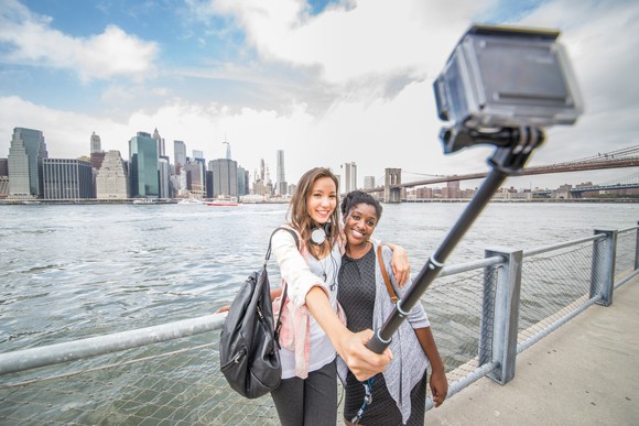 Two women take a selfie with a sports camera.
