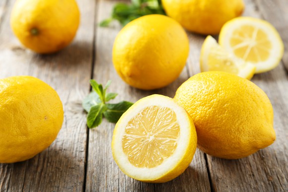 Lemons sitting on a wooden surface.