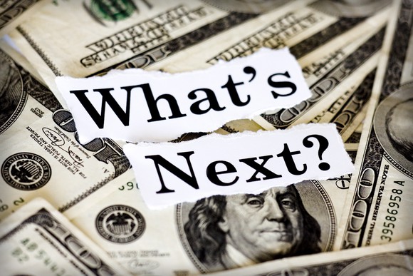 The words "What's Next" written in paper on top of a pile of cash.