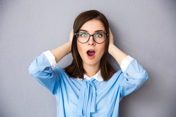 Woman holding her hand on her head with mouth open.