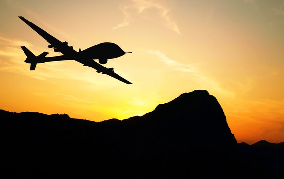 Drone silhouetted against a mountain sunset