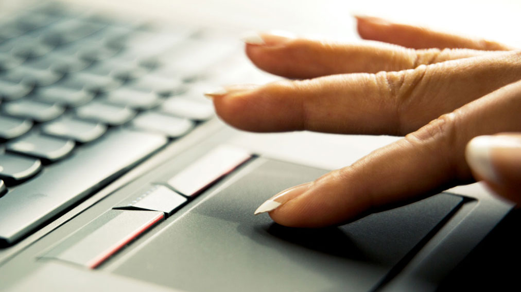 A hand using a Synaptics touchpad on a laptop.