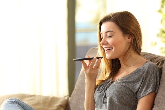 Girl smiling speaking into smartphone held in front of her.